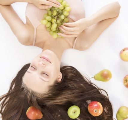 Woman lying down with fresh fruits symbolizes beauty and wellness.