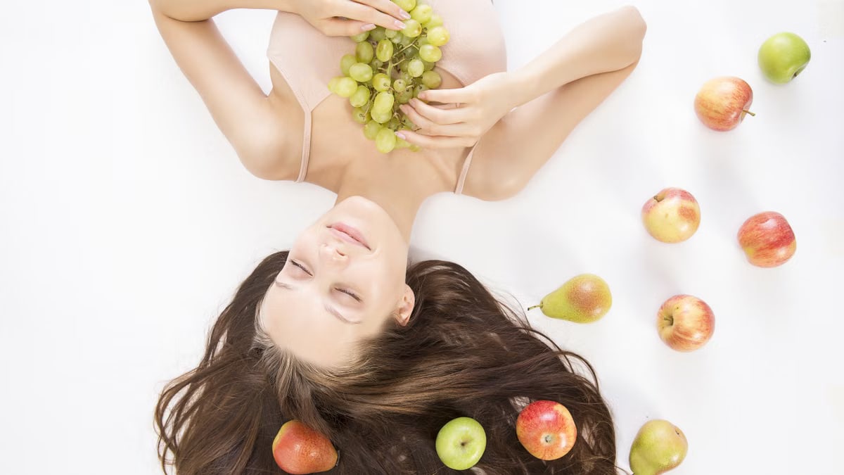 Woman lying down with fresh fruits symbolizes beauty and wellness.